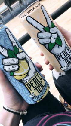 two people holding up cans of juice in front of a basketball court with the words peace on them