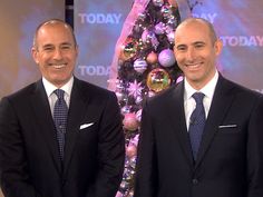 two men in suits standing next to each other near a christmas tree with ornaments on it