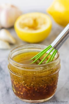 a jar filled with sauce next to lemons and garlic