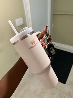 a person holding a coffee cup with a straw in it's mouth and a cell phone on the other hand