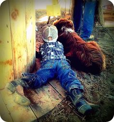 a small child laying on the ground next to a brown bear and wearing a mask