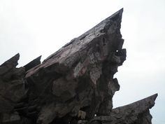 a large rock formation on the side of a mountain with rocks sticking out of it's sides