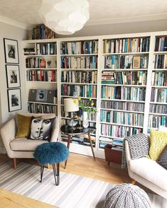 a living room filled with lots of books and furniture next to a wall full of bookshelves