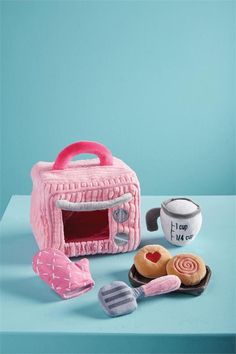 a pink toy microwave oven sitting on top of a table next to cookies and cupcakes