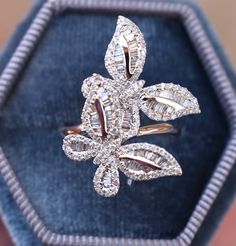 a diamond flower ring sitting in a velvet box