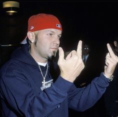 a man wearing a red hat and making the peace sign with his hands in front of him