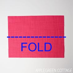 a piece of red fabric with the word fold in blue on it and an apple green cottage