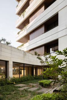 an apartment building with several balconies on the top floor and plants growing in the yard