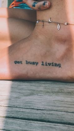 a woman's foot with the words get busy living tattooed on her left ankle