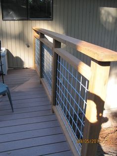 a wooden deck with chairs on it next to a wall and windows in the background