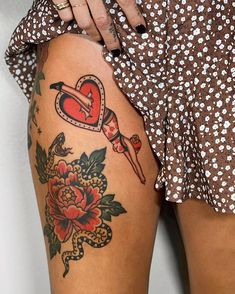 a woman's thigh with tattoos and flowers on her leg, showing the tattoo design