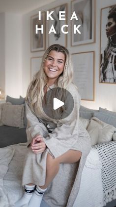 a woman sitting on top of a bed covered in a blanket and smiling at the camera