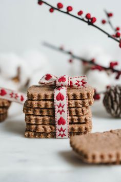 a stack of cookies with a bow tied around the top and some pine cones in the background