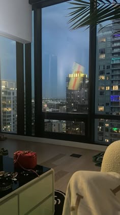 a living room filled with furniture and large windows overlooking the city at night in the distance