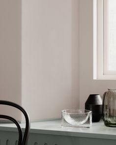 two vases sitting on top of a counter next to a chair and window sill