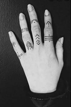 two fingers with tattoos on them, one is holding the other's hand up