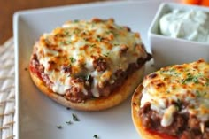 two mini pizzas with cheese and meat on them