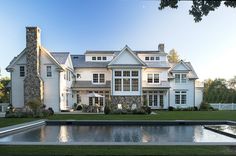 a large white house with a pool in the front yard and water feature on the lawn