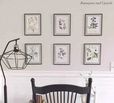 a wooden chair sitting in front of a table with pictures on the wall behind it