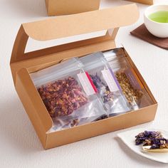 an open box filled with different types of food next to a cup and saucer