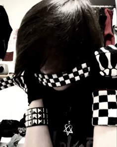 a woman with black and white checkered gloves covering her face in front of a mirror