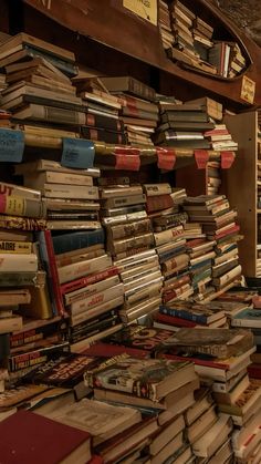 a large amount of books are stacked on top of each other in a room with wooden shelves