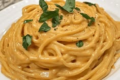 a white plate topped with pasta covered in sauce and garnished with parsley