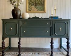 a green dresser with two vases sitting on top of it next to a painting