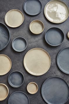 many plates are arranged on a table with black and tan ones in the middle one is empty