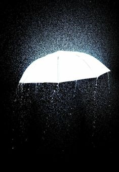 a white umbrella in the rain on a black background