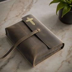 a brown leather bible cover with a cross on the front, and a plant in the background