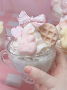 a person holding a small cup filled with whipped cream and candies in the shape of animals