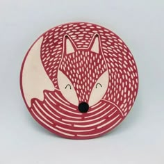 a red and white plate with a fox design on it's face in front of a gray background