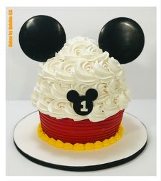 a mickey mouse cake with white frosting and black ears