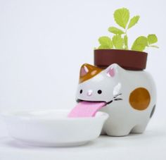 a ceramic cat with a flower pot on it's head is eating from a bowl