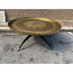 a golden tray with black legs on the sidewalk