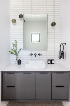 a bathroom with a sink, mirror and two lights on the wall above it's counter