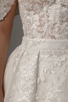 the back of a woman's wedding dress with white lace and flowers on it