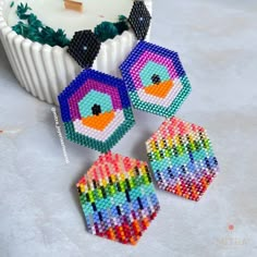 three colorful bird shaped beaded earrings next to a cupcake