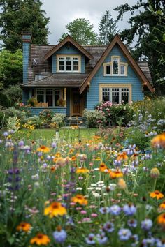 a blue house surrounded by wildflowers and trees