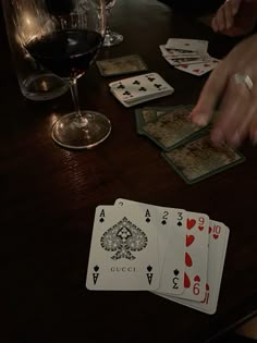 playing cards on a table next to a glass of wine