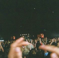 a crowd of people at a concert with their hands in the air and one person holding up his hand