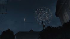 fireworks are lit up in the night sky above houses and power lines as seen from an alleyway