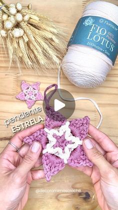 two hands are holding a crocheted star ornament and yarn is next to it