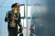 a man in a racing suit with a trophy on his head walking down the street