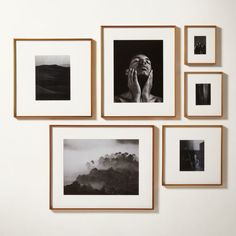 four framed photographs hang on the wall above them are black and white photos, with one woman's head resting her hands to her face