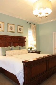 a bedroom with blue walls and white bedding, framed pictures above the headboard