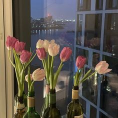 three wine bottles with flowers in them on a window sill