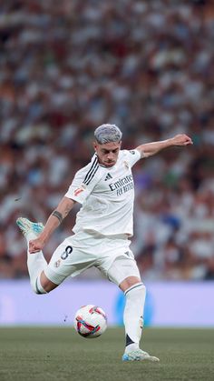 a man kicking a soccer ball on top of a field