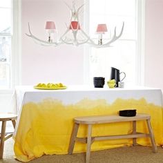 a dining room table with yellow and white cloth on it, next to two chairs